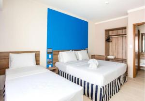 two beds in a room with a blue wall at Apartamento Ondas Resort in Porto Seguro