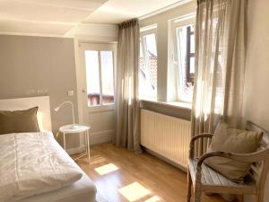 una camera da letto con un letto, una sedia e finestre di LA PETITE MAISON Fachwerkhaus am Rande des Sauerlandes in Warburg a Warburg