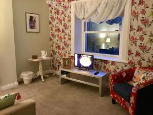 una sala de estar con TV en una mesa y una ventana en The Glen Mona Hotel en Maughold