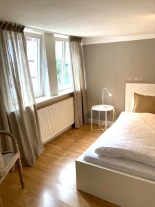 una camera da letto con un letto, un tavolo e finestre di LA PETITE MAISON Fachwerkhaus am Rande des Sauerlandes in Warburg a Warburg