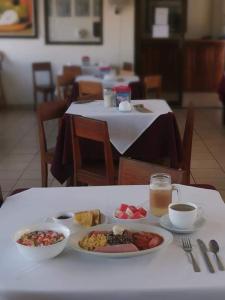 einen Tisch mit Teller mit Lebensmitteln und ein Glas Saft in der Unterkunft Hotel La Siesta in Liberia