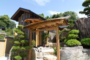 ein Haus mit einer hölzernen Pergola im Garten in der Unterkunft Ryokan Shinsen in Takachiho