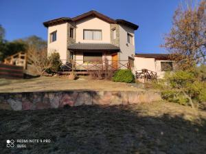 a white house with a fence in front of it at Casas Altas VGB in Villa General Belgrano
