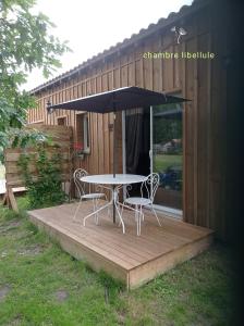 un tavolo con due sedie e un ombrellone su una terrazza di les chambres du pont des chèvres a Commensacq