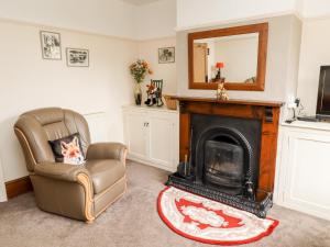 a living room with a chair and a fireplace at Bumble Bee Cottage in Alford