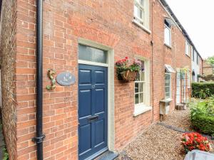 a brick house with a blue door and a window at Bumble Bee Cottage in Alford