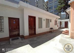 un edificio blanco con puertas marrones y una mesa en una calle en Hostel Luz Robles, en Quito
