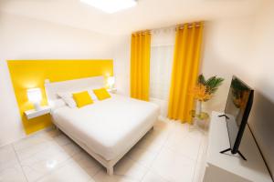 een slaapkamer met een groot wit bed en gele gordijnen bij Eden Blue vue Mer et Piscine in Sainte-Anne
