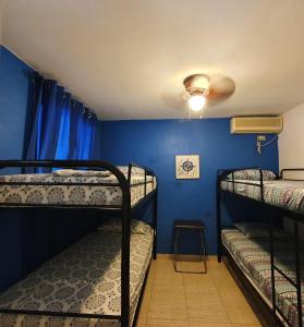 a room with three bunk beds and a blue wall at Hostal Villa Mayte Coronado in Las Lajas