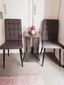 two chairs sitting next to a table with a vase at Deluxe Spacious Apartment in Chadwell Heath, London in Goodmayes