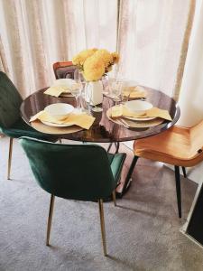 einen Holztisch mit Stühlen und einen Tisch mit Tellern und Gläsern in der Unterkunft Deluxe Spacious Apartment in Chadwell Heath, London in Goodmayes