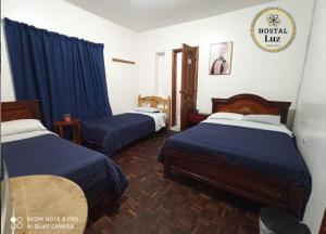 Habitación de hotel con 2 camas con sábanas azules en Hostal Luz Wilson, en Quito