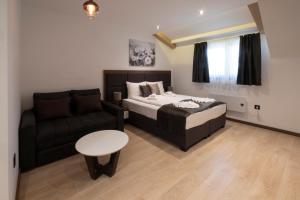a bedroom with a bed and a couch and a table at Mila apartmani Kopaonik in Kopaonik +29 photos