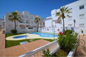 widok na budynek z basenem i palmami w obiekcie Apartamento-Solárium playa Marina de la Torre w mieście Mojácar