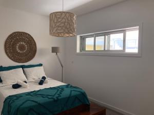 a bedroom with a bed with a green blanket and a window at Sesimbra by the sea in Sesimbra