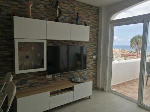 a living room with a television and a brick wall at Costa Adeje Apartments in Adeje +14 photos