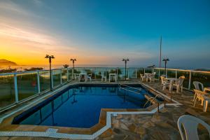 a pool on the roof of a building with a sunset at UPG Hotel in Ubatuba