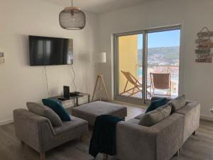 a living room with a couch and chairs and a tv at Sesimbra by the sea in Sesimbra