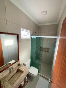 uma casa de banho com um WC e uma cabina de duche em vidro. em Bella Spiaggia Suítes em Flecheiras