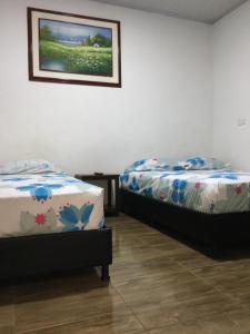 dos camas sentadas una al lado de la otra en una habitación en HOTEL LA CASONA, en Buga