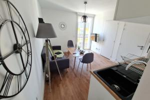 a kitchen and living room with a large clock on the wall at Le Poulorio 11 - T2 - Proche Gare By Locly in Lorient +2 photos