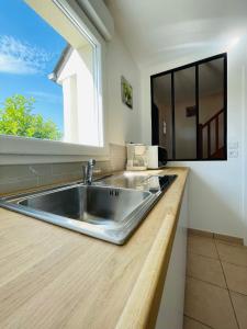 uma cozinha com um lavatório de aço inoxidável e uma janela em Maison rénovée dans quartier résidentiel aux portes de Tours em Véretz