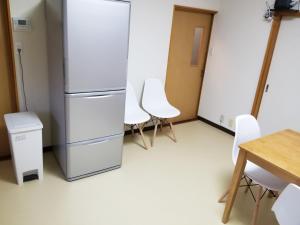 eine Küche mit einem Kühlschrank sowie einem Tisch und Stühlen in der Unterkunft コンドミニアム海のまんまえ荘 in Kangoji