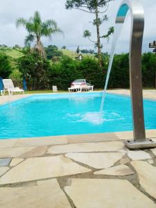een blauw zwembad met een fontein bij Pousada voo livre in Extrema
