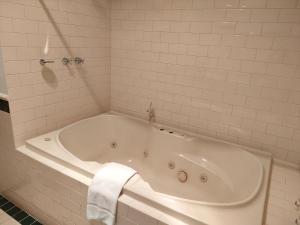 uma banheira branca numa casa de banho com azulejos brancos em Stay Margaret River em Margaret River