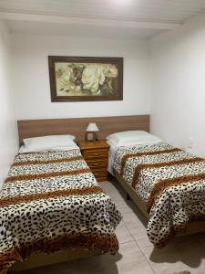 2 camas en una habitación con una foto en la pared en Casa da Silene, en Gramado