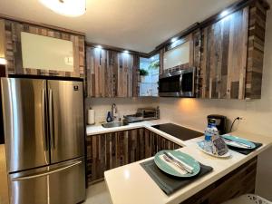 una cocina con nevera de acero inoxidable y armarios de madera en Expansive Paradise with Private Jacuzzi and Tropical Patio, en Ponce