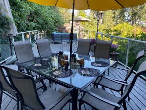 a table with chairs and an umbrella on a deck at Kye Bay BnB - A Place to Breathe in Comox