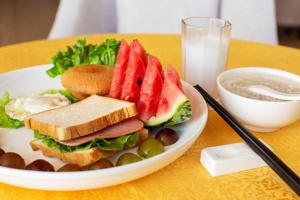 a plate of food with a sandwich and a bowl of milk at GreenTree Inn Jiangsu Suzhou Shengze Bus Station Business Hotel in Suzhou