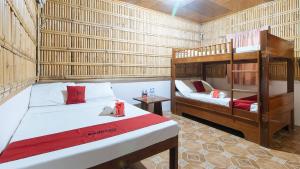 a room with two beds and a bunk bed at RedDoorz Hostel @Megans Paradisio Beach Resort in Zambales