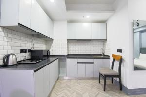 a kitchen with white cabinets and a chair in it at BedChambers Serviced Apartments - Cyber City in Gurgaon
