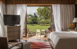 a bedroom with a bed and a television and a patio at Four Seasons Resort Langkawi in Tanjung Rhu