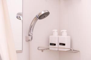 a bathroom with a shower head and two bottles on a shelf at ELE Hotel 東上野 in Tokyo