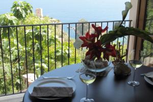 a table with wine glasses and flowers on a balcony at Torre Bennistra in Scopello