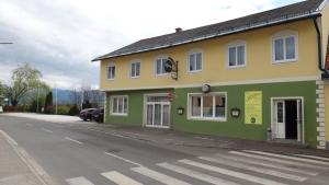 un edificio verde y amarillo al lado de una calle en sWirtshaus M&N, en Zeltweg