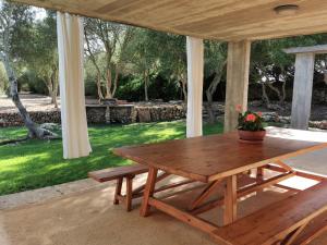 einen Holztisch und eine Bank auf einer Terrasse in der Unterkunft Cucurutxa in Maó