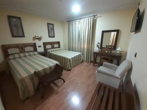 1 dormitorio con 2 camas, silla y espejo en Hotel El Pentágono en Muñana