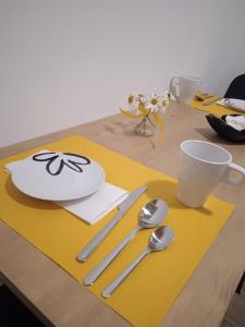 Lozzo Cadore的住宿－La Mansarda，一张桌子,上面有盘子和勺子,放在黄色的垫子上
