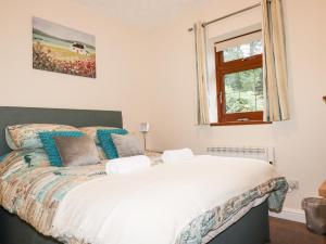 a bedroom with a large white bed with a window at Jasmine Cottage in Liskeard
