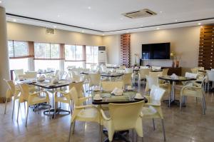 a dining room with tables and white chairs at Hotel 2001 in Maputo