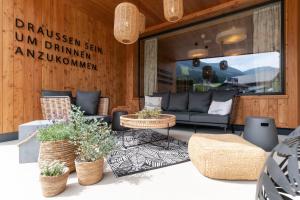 a living room with a couch and chairs and plants at Apart & Suiten Hotel WEIDEN in Schladming