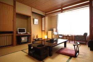 a living room with a coffee table and a television at Hotel Towadaso in Towada