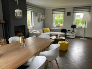 a living room with a wooden table and white chairs at BB La Marinière in Theux