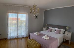 a bedroom with a large bed and a chandelier at Pine Tree Villa in Pakoštane