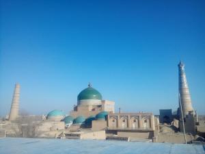 a mosque with a green dome and two towers at Fayz Guest House in Khiva