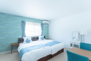 um quarto com uma cama grande e uma mesa em Villa Capri Miyakojima em Ilhas Miyako